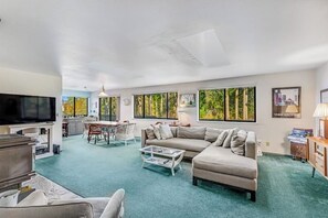 Una sala de estar moderna con televisor, sofá, mesa de centro y un comedor con sillas.