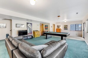 Een woonkamer met een pooltafel, een bank en een televisie.
