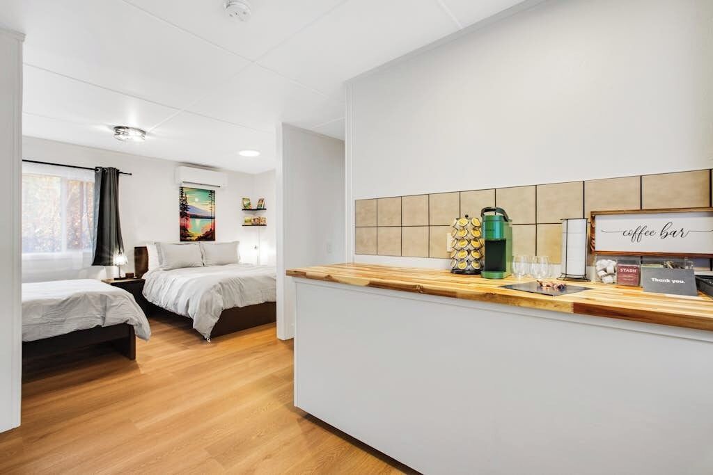 A hotel room with two beds, a kitchenette, and a coffee bar.