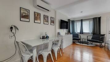 Un soggiorno moderno con zona pranzo, televisione a schermo piatto e finestra con tende.