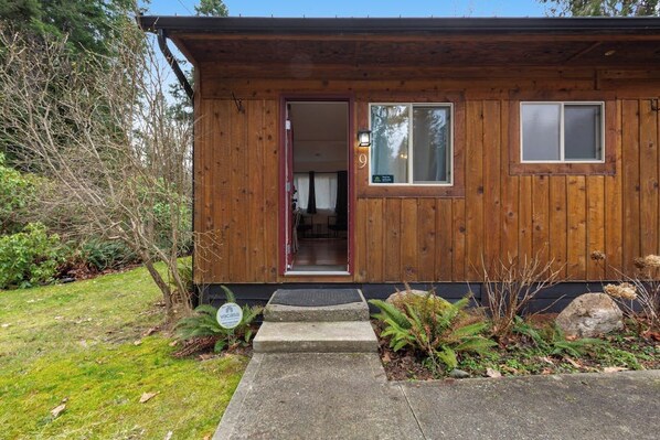 Une cabane en bois avec une porte, des fenêtres et un petit porche.