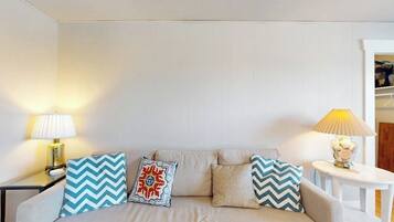 A neutral-colored sofa with patterned cushions, two bedside lamps, and a small table with a lamp.