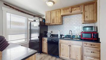 A kitchen with wooden cabinets, a black refrigerator, a dishwasher, a microwave, and a toaster.