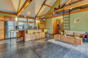 Una cocina amplia con una isla central, vigas de madera y un ventanal grande.