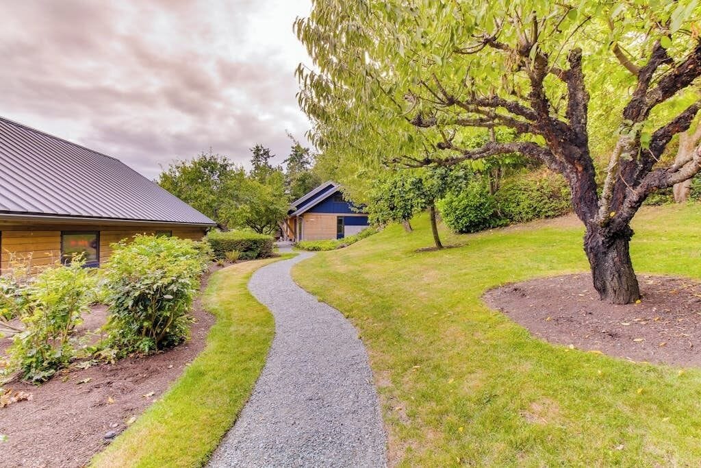 A residential property with a paved pathway leading to a house with a sloped roof.