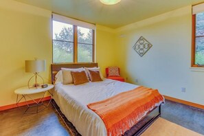 A bedroom with a bed, a bedside table, a lamp, and a window.