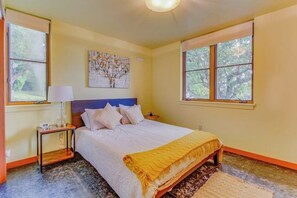 Un dormitorio con una cama, una mesita de noche, una lámpara y un cuadro en la pared.