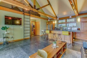A spacious kitchen with a large island, wooden beams, and a sliding door leading to another room.