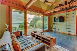 Una sala de estar moderna con un sofá de cuero, una mesa de centro de madera y un ventanal con vistas al exterior.