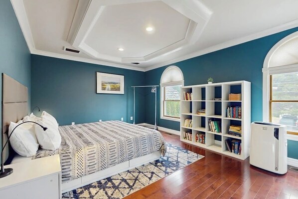 Een slaapkamer met een bed, een boekenkast, een radiator en een raam.