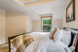 A bedroom with a bed, a window, and a painting on the wall. - Idyllic woodsy 6BR with firepit & two kitchens (Camano Island)