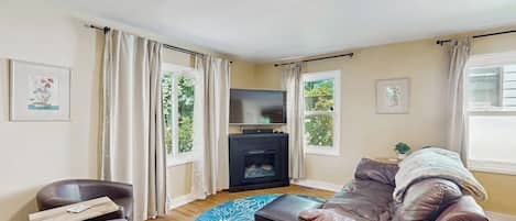 Una sala de estar con un sofá, un televisor y una chimenea.