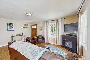 A room with a bed, two armchairs, a television, a fireplace, and a window with curtains. - 2 BR charming cotttage, pet-friendly, near Seattle (Seattle)