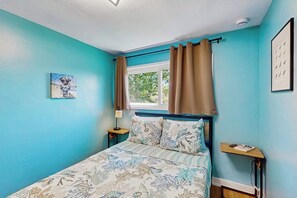 A bedroom with a bed, a window with curtains, a bedside table, and a wall with a framed picture. - 2 BR charming cotttage, pet-friendly, near Seattle (Seattle)