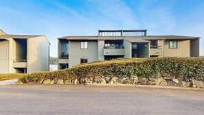 Un moderno edificio residencial de varios pisos con un muro de contención de piedra y cielo despejado.