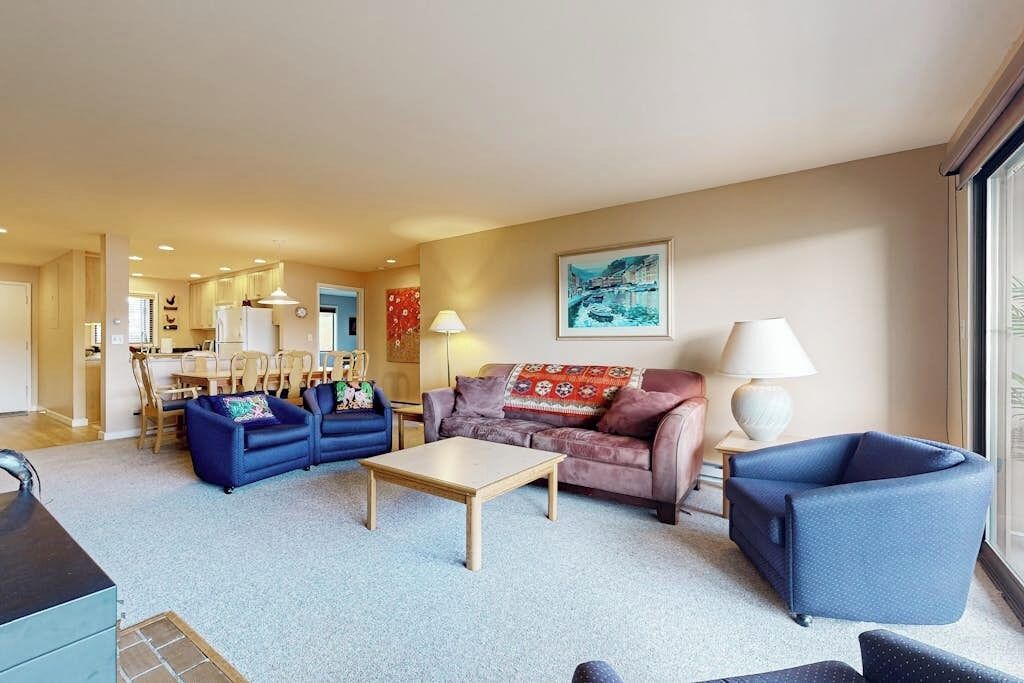 A living room with a sofa set, a coffee table, and a dining area in the background.