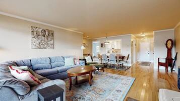 A living room with a sofa, coffee table, and rug. There is a dining area with chairs and a table.