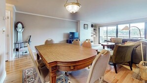 Amplia sala de estar con mesa de comedor de madera, asientos cómodos y ventanas grandes que ofrecen vistas.