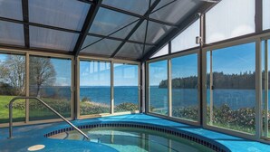 Una piscina techada con vistas al lago y árboles.