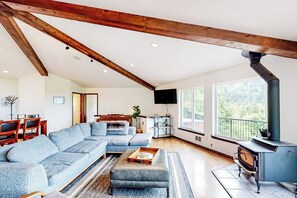 Ein geräumiges Wohnzimmer mit einer großen Eckcouch, einem Kamin und einem Essbereich mit Holztischen und -stühlen.