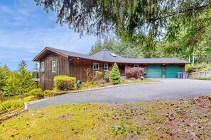 Ein Holzhaus mit Garage, umgeben von viel Grün und einer Auffahrt.