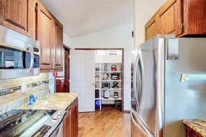 Eine Küche mit Holzschränken, einem Edelstahlkühlschrank, einer Mikrowelle und einem eingebauten Backofen.