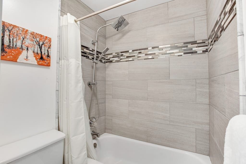 Un baño moderno con ducha, bañera y pared de azulejos.