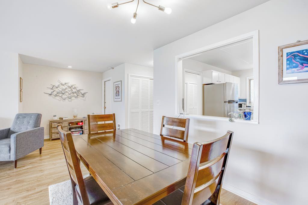 Un coin repas avec une table et des chaises en bois, un fauteuil gris et une œuvre d’art accrochée au mur.