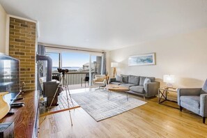 Una sala de estar moderna con balcón, televisor, sofá y mesa de centro.