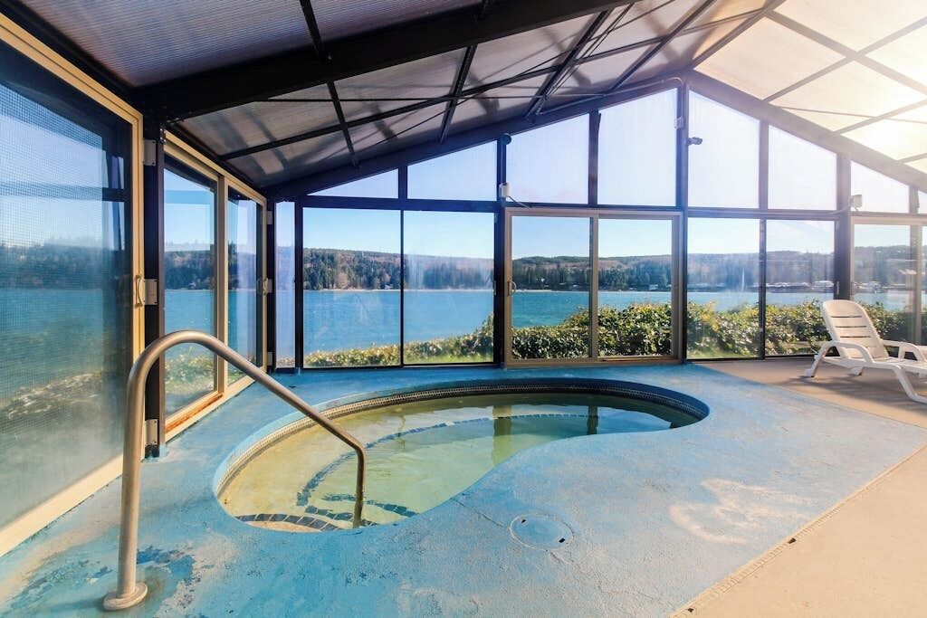 An indoor swimming pool with a view of a lake and hills.