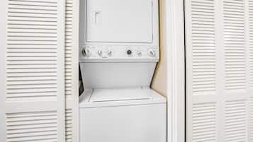 Un ensemble lave-linge et sèche-linge blancs, doté d’un panneau de commande, situé dans une pièce dont les portes de placard sont blanches et à persiennes.