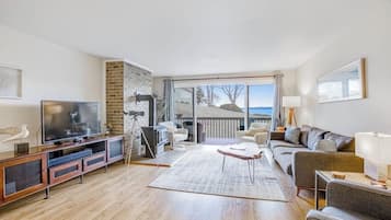 A spacious living room with a large TV, comfortable seating, a fireplace, and a view of the outdoors.