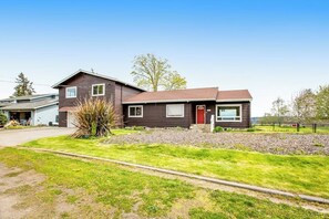 Een huis met twee verdiepingen, een rode deur, een garage en een verzorgd gazon.