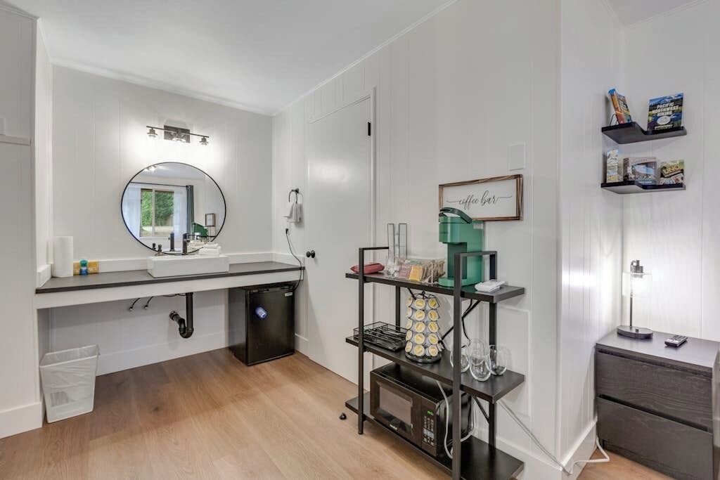 Un baño moderno con lavabo, espejo y cafetera.