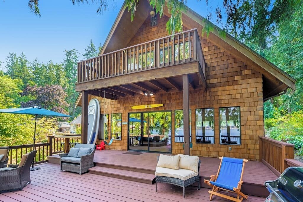 A wooden cabin with a deck, outdoor seating, and a slide.
