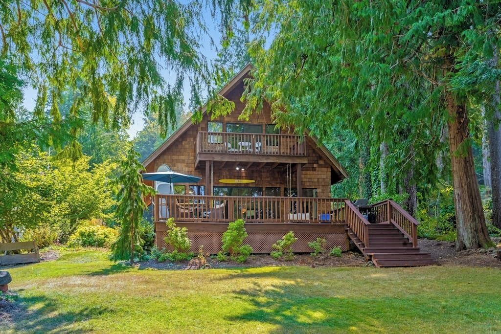 A cabin with a balcony, surrounded by trees.