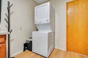 A laundry room with a stacked washer and dryer, a wooden door, and a coat rack. - 4BR charming lakeside home with beach access (Olympia)