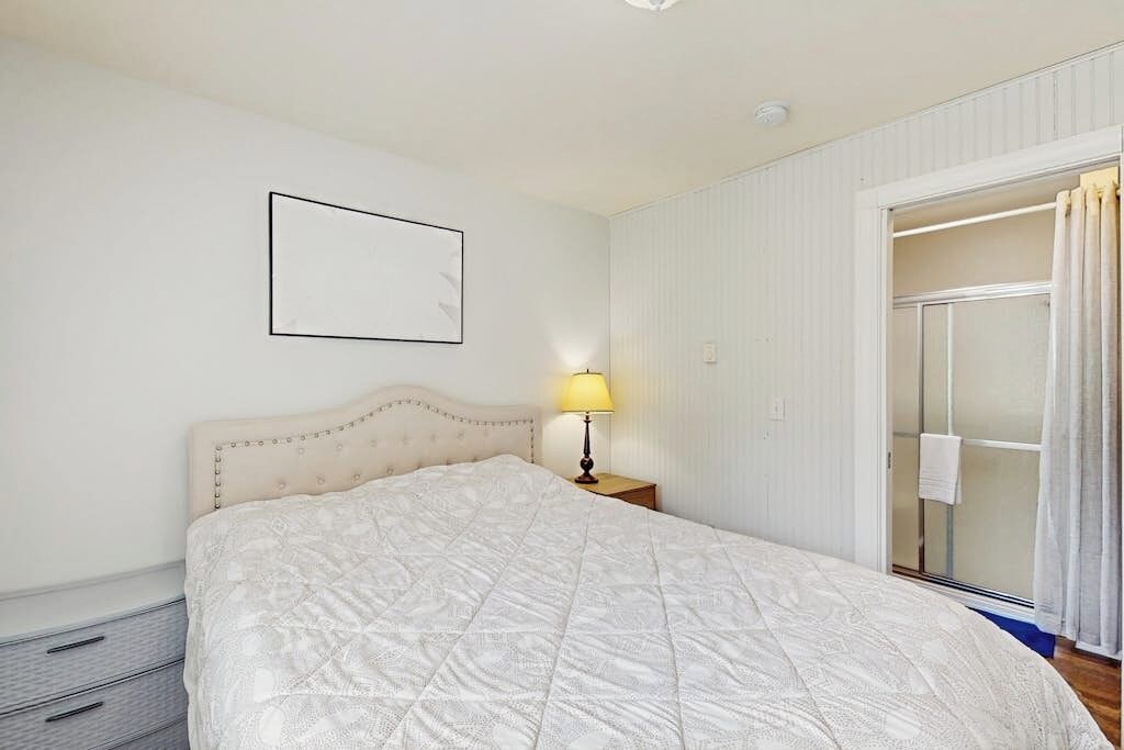 A bedroom with a bed, a bedside lamp, a wardrobe, and a sliding glass door.