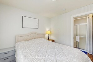 Ein Schlafzimmer mit Bett, Nachttischlampe, Kleiderschrank und einer Schiebetür aus Glas.