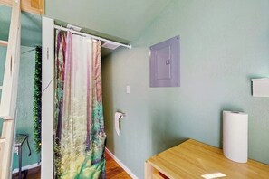 Een badkamer met douchegordijn, toiletrolhouder en een houten tafel.