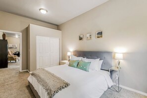 A bedroom with a large bed, two bedside lamps, and a door. - Island 3BR with firepit & port & mountain views (Camano Island)