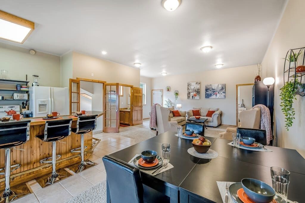 A modern kitchen with a dining area, featuring a bar counter, stools, and a central island with seating.