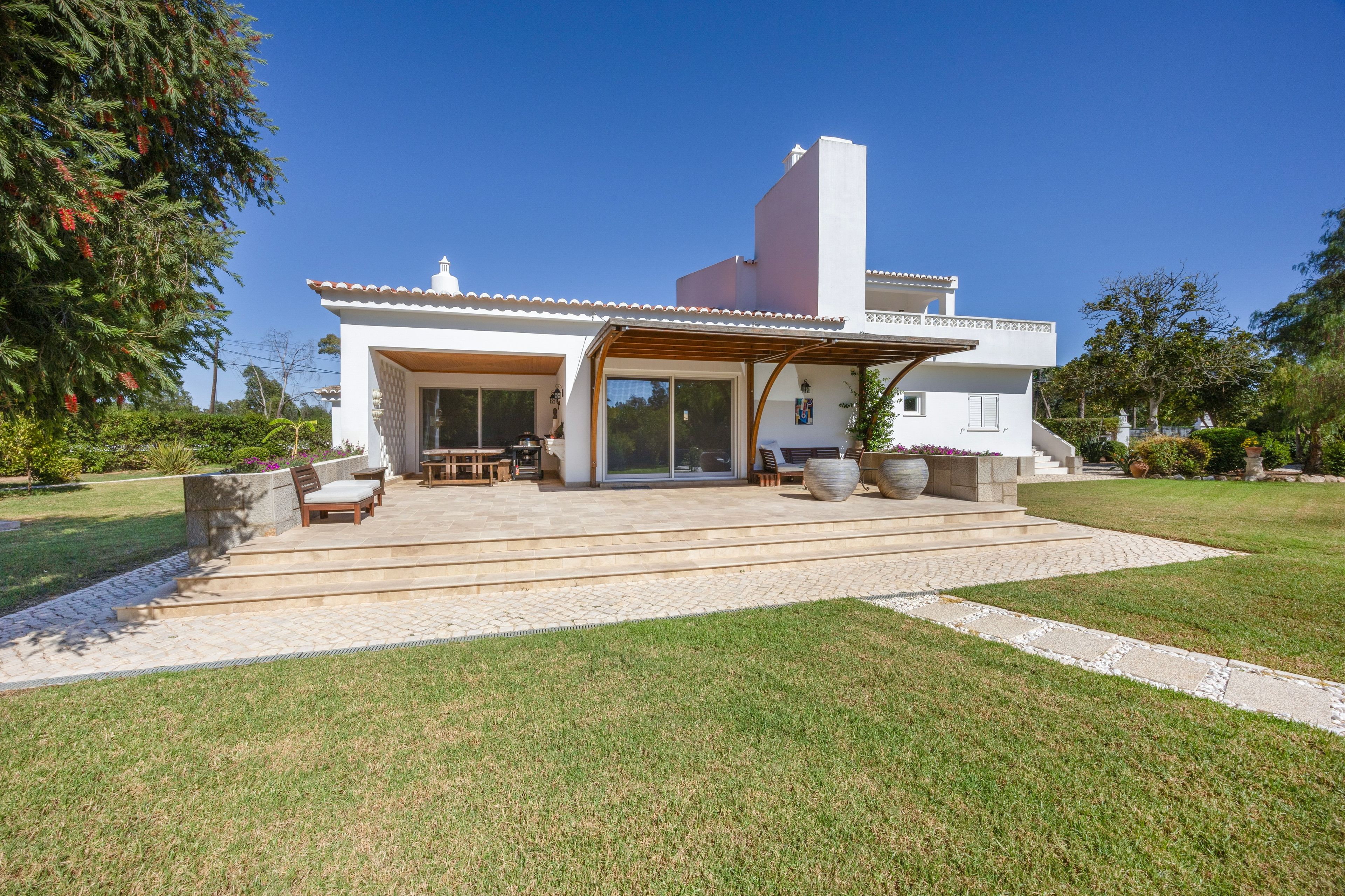 A modern house with a patio, outdoor seating, and a well-maintained lawn.