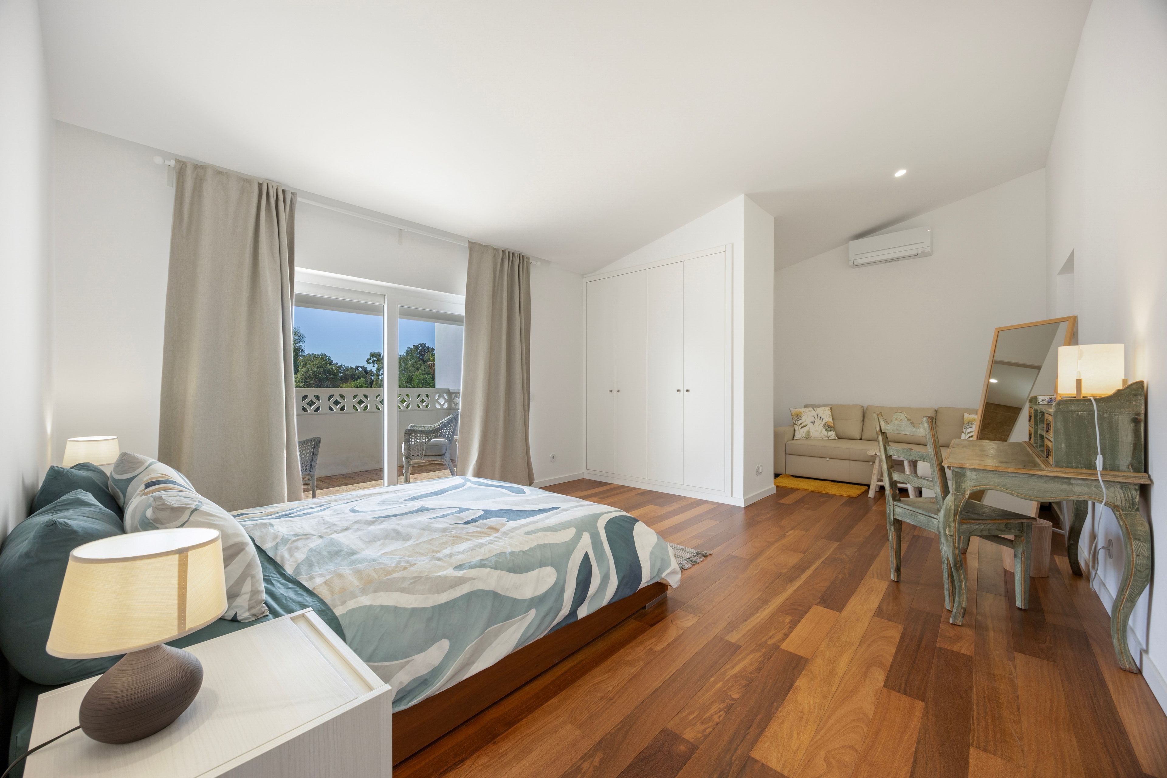 A bedroom with a bed, a desk, and a sofa.