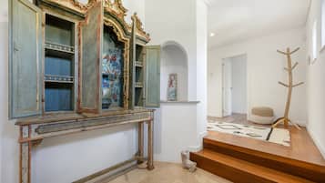 A staircase with a patterned rug, a wooden coat rack, and a decorative mirror with ornate frames.