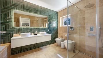 Un baño moderno con ducha envuelta en cristal, tocador con doble lavabo y un espejo grande.