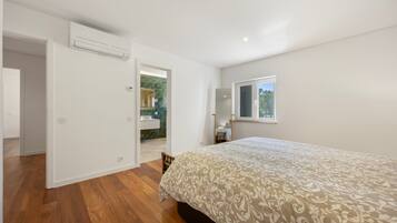 Une chambre à coucher avec un lit, une fenêtre et une salle de bain visible à travers une porte ouverte.