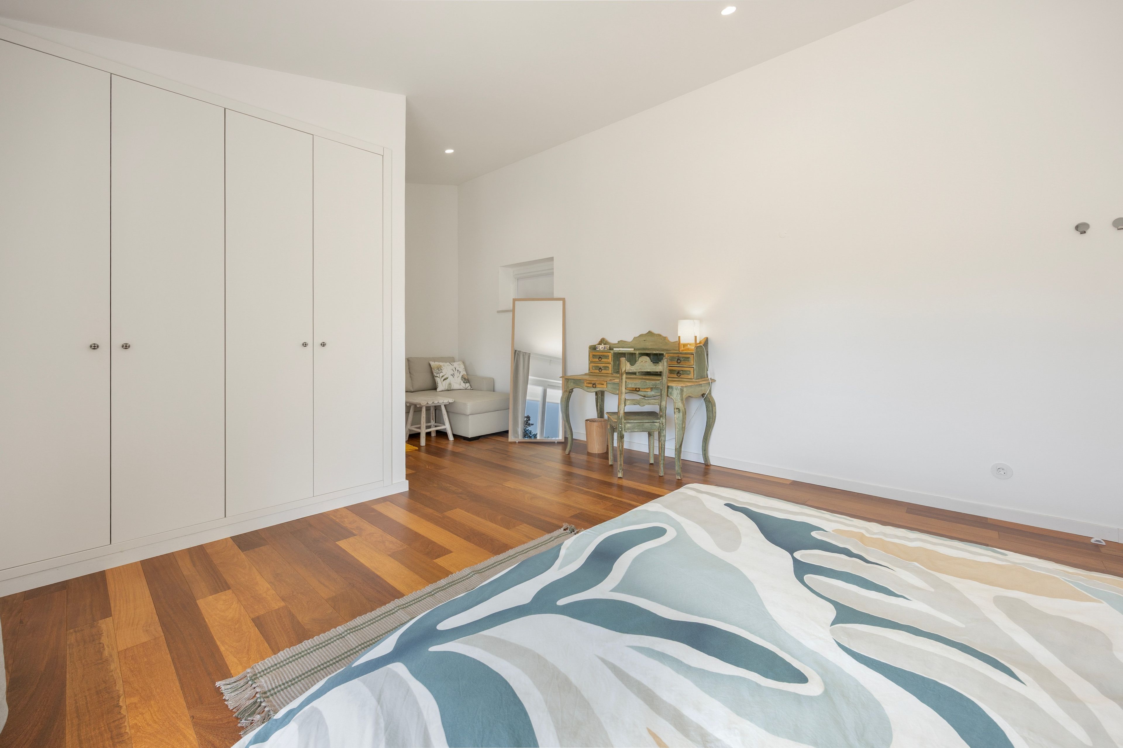 A bedroom with a bed, a wardrobe, a desk, and a chair.