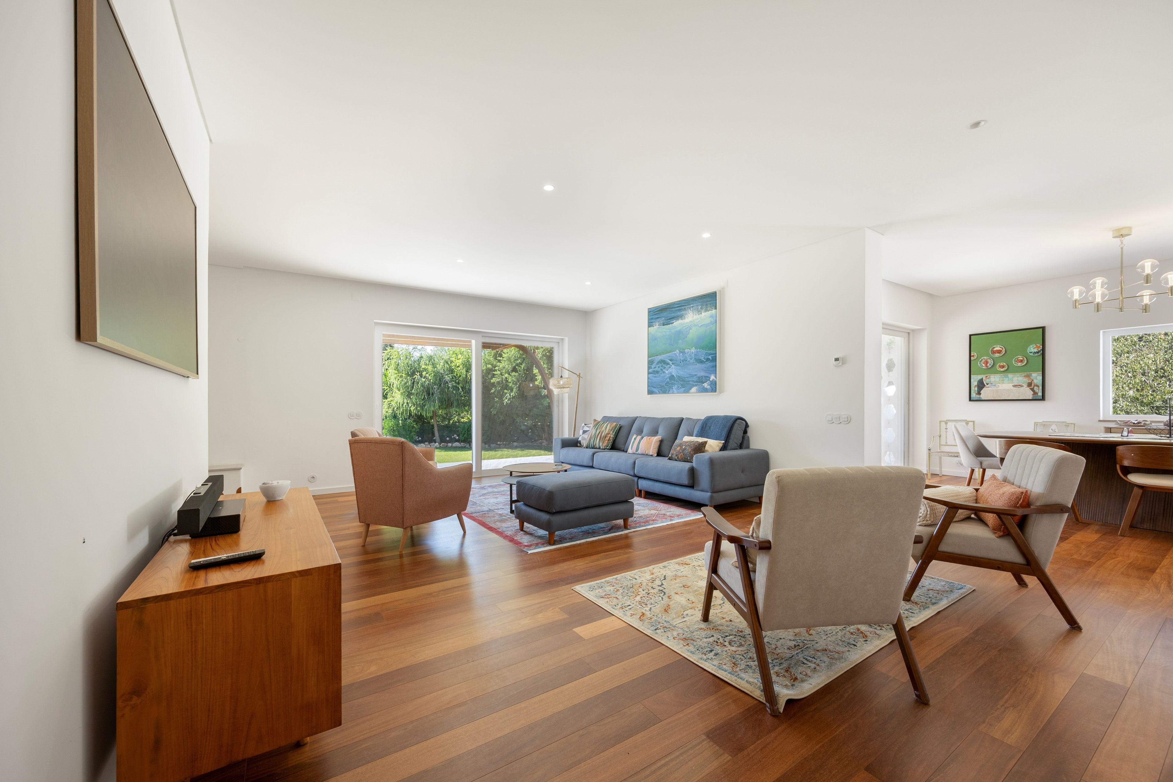 A modern living room with a sofa, chairs, a coffee table, and a dining area with a table and chairs.