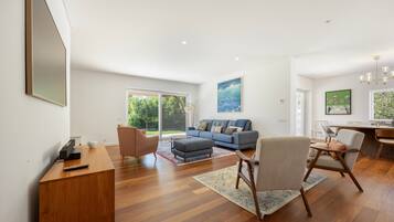 A modern living room with a sofa, chairs, a coffee table, and a dining area with a table and chairs.